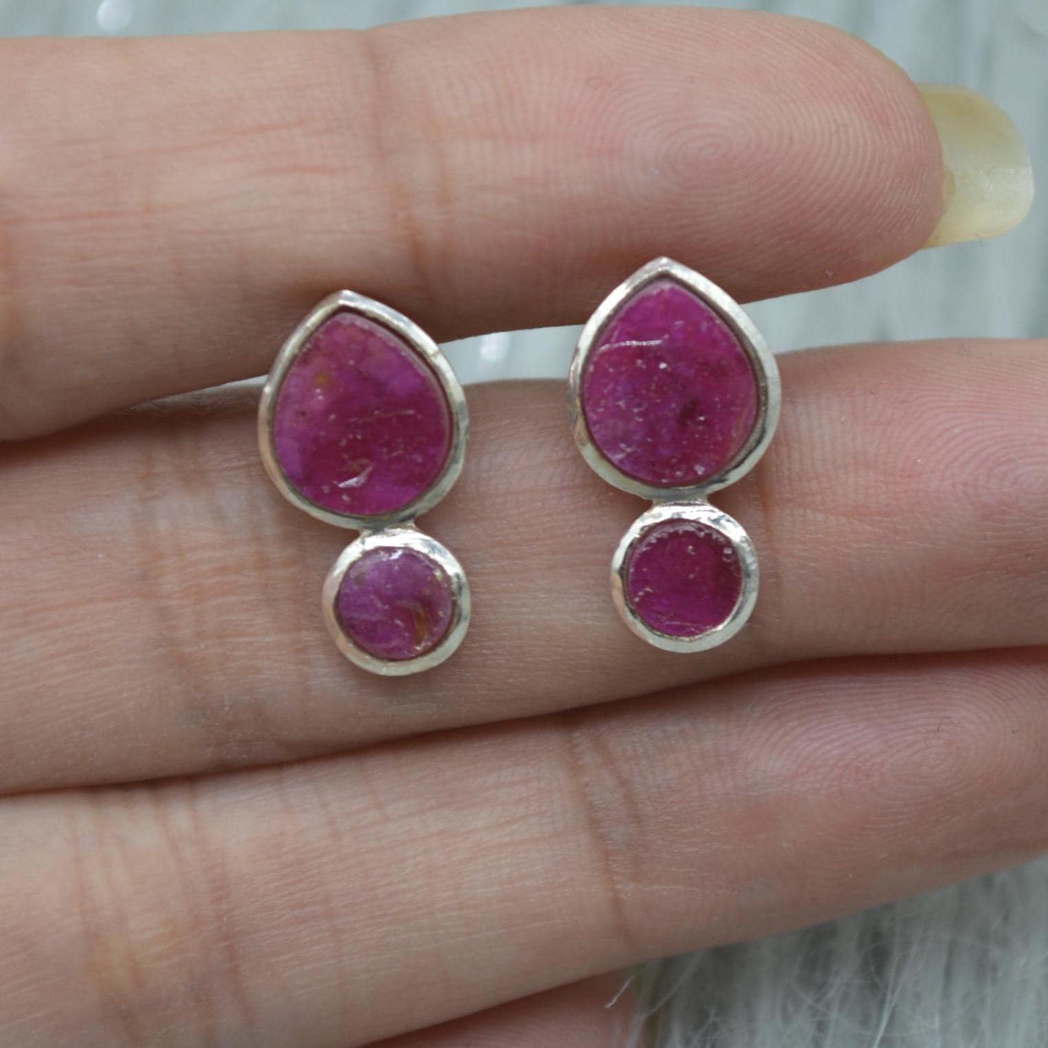 Small sterling silver stud earrings with two raw ruby gems in round and teardrop shape